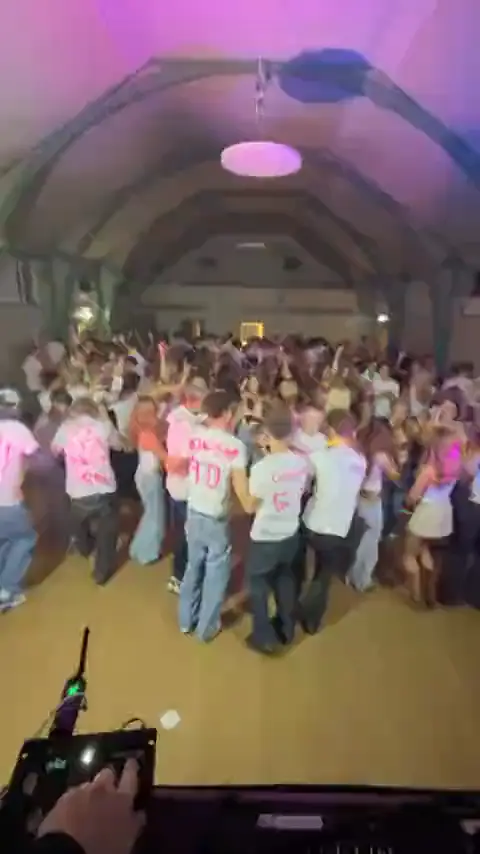 Elever danser i en stor hal til en efterskolefest, set fra DJ-pulten