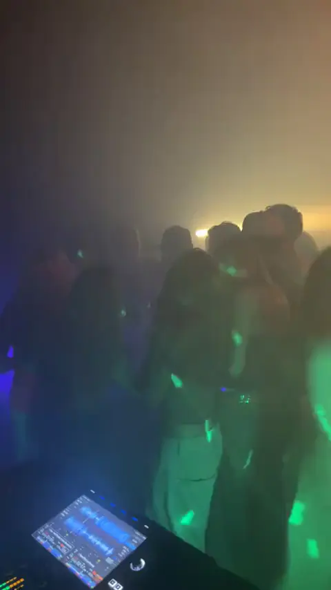 Gæster med armene i vejret på dansegulvet til en konfirmation, set fra DJ-pulten