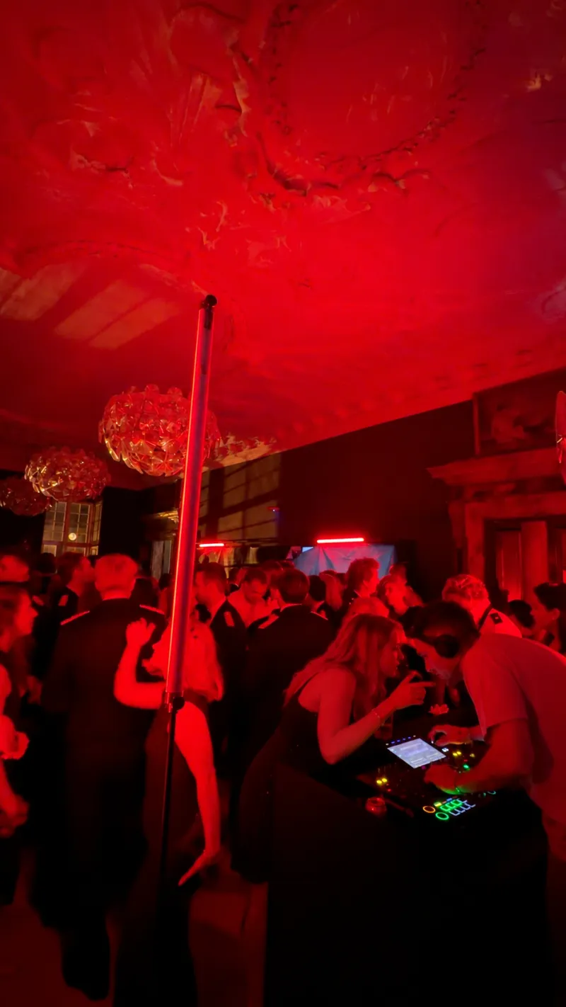 Gæster ved DJ-pulten midt i festen i rødt lys