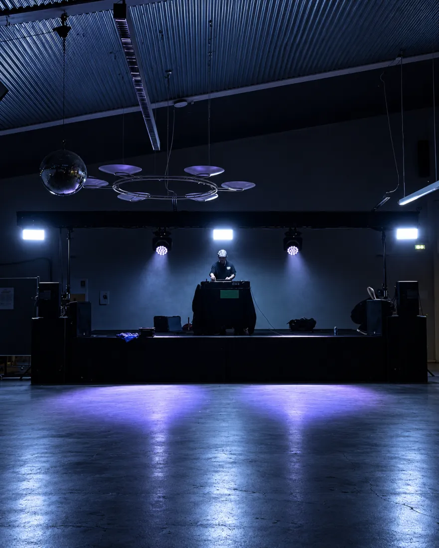 DJ bag pulten på scene med spots og diskokugle i blåt lys