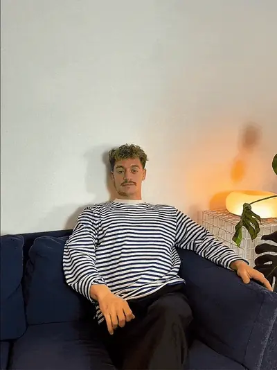 Arthur Cohrt Hillgaard, medstifter af DJTILBUD, sidder i en sofa i stribet trøje