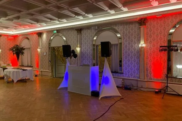 DJ-pult, højttalere og lys sat op i en festsal